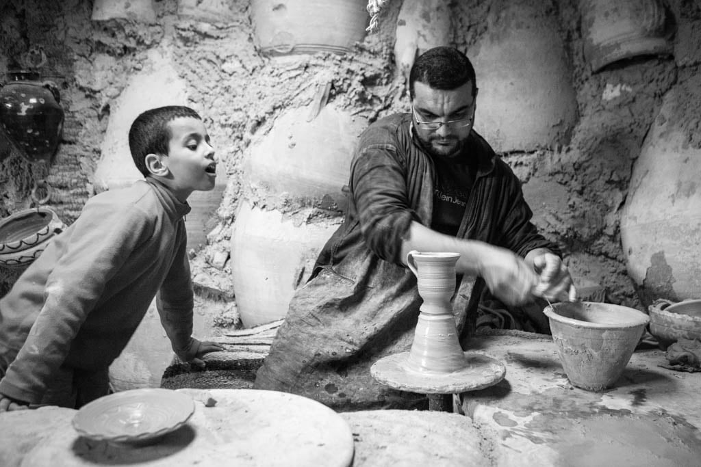 Niño mirando como un artesano hace una pieza de barro